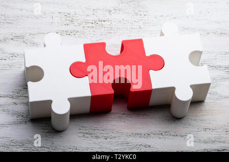 Close-up Of White And Red Jigsaw Puzzle Block On White Textured Background Stock Photo