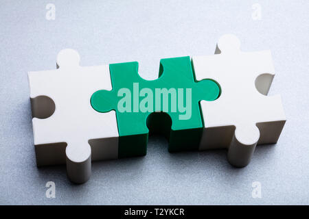 Close-up Of White And Green Jigsaw Puzzle Block On White Textured Background Stock Photo