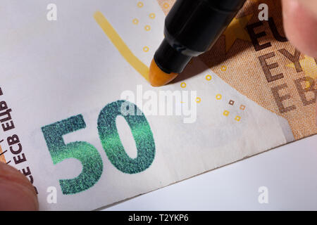Close-up Of Hand Writing On Banknote With Yellow Marker Stock Photo