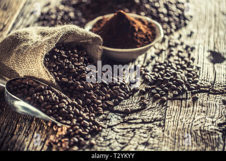 Coffee beans in burlap sack on old wooden table. Stock Photo