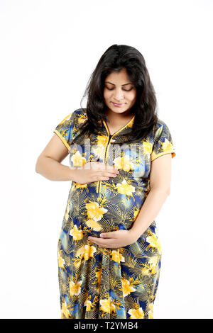 Beautiful pregnant woman is touching belly. Isolated on the white background. Stock Photo