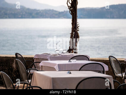 Image of decorated restaurant table on a terrace with view on lago maggiore with mountains in the background Stock Photo