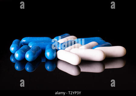 Lot of whole blue and white sweet licorice comfit isolated on black glass Stock Photo