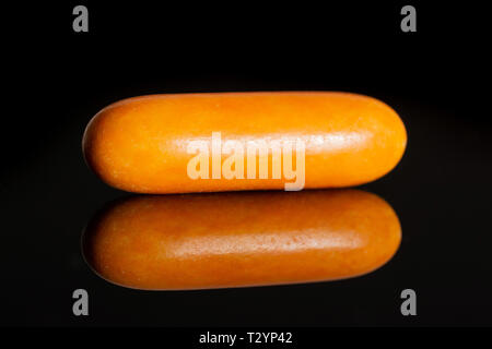 One whole orange sweet licorice comfit isolated on black glass Stock Photo