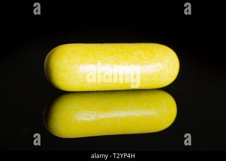 One whole yellow sweet licorice comfit isolated on black glass Stock Photo