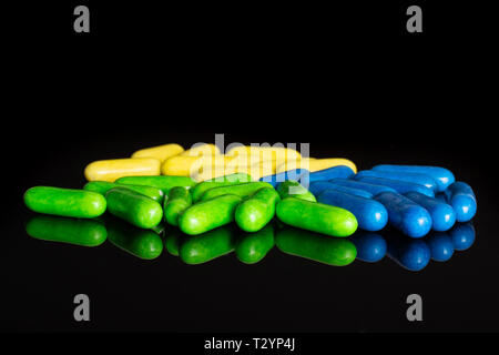 Lot of whole green blue and yellow sweet licorice comfit isolated on black glass Stock Photo