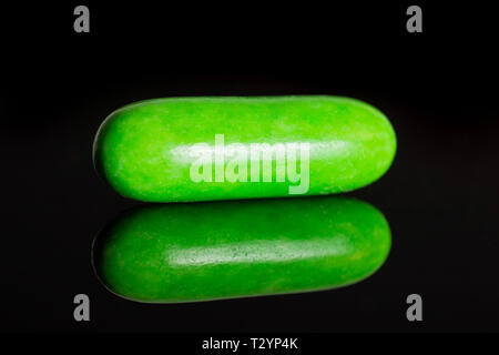 One whole green sweet licorice comfit isolated on black glass Stock Photo