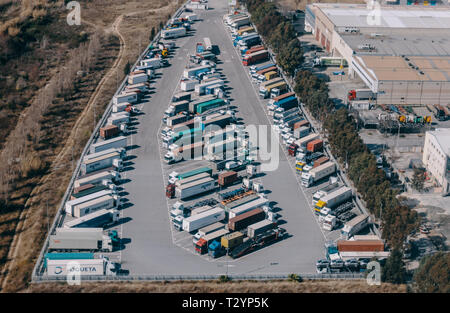 Haulage trucks sit parked in a distribution warehouse in an aerial photograph taken in public airspace over Zona Franca, Barcelona. Stock Photo