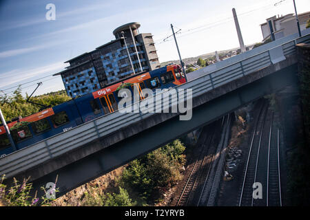 A Sheffield SuperTram crosses a bridge over the railway lines early in the morning, near the city centre Stock Photo