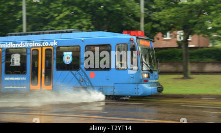 A Sheffield Supertram sprays water from its tracks as it drives through standing water on the track Stock Photo