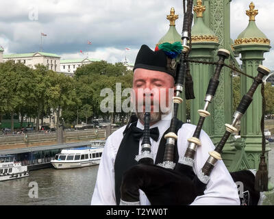 LONDON, ENGLAND, UK - SEPTEMBER 17, 2015: a bagpipes payer performs on a bridge over the river thames in london, england Stock Photo