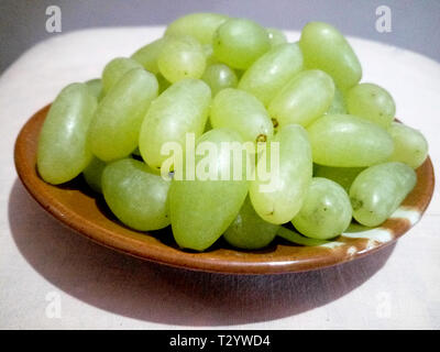 Brown ceramic tray containing green seedless grapes shining in sunlight Stock Photo