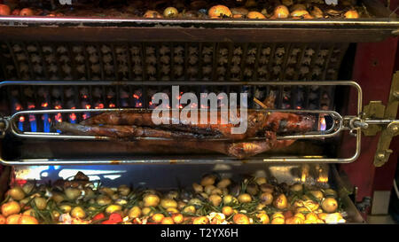 a suckling pig, chickens and vegetables being roasted on a rotisserie at a restaurant in paris Stock Photo