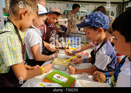 Tyumen, Russia - August 26, 2016: Open Day of Sberbank for kids. Young confectioners. Children do sweet candies Stock Photo