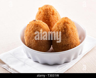 Three deep fried Arancini, breaded rice balls with a savory stuffing, from Sicily served in a bowl with white napkin Stock Photo