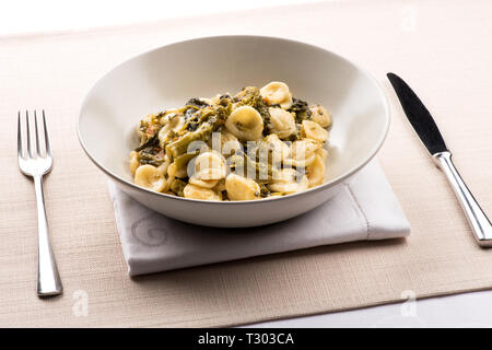 Orecchiette con Cime di Rapa, or a bowl of orecchiette pasta with broccoli rabe, a regional dish from Puglia, Italy served in a bowl at table Stock Photo