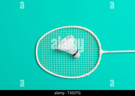 Shuttlecock and racket for playing badminton on a cyan background. Stock Photo