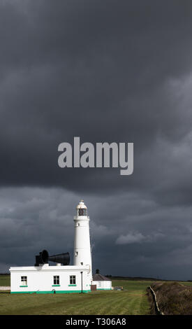 The Nash Point Lighthouse looking out over Bristol Channel against a dark sky on the Glamorgan Heritage Coast south Wales in a portrait format. Stock Photo