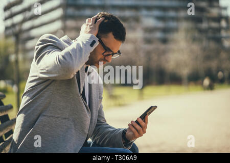 Young businessman is using smartphone in park. Stock Photo