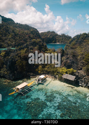 An aerial shot of a  secluded beach hut with boats in Coron, Philippines Stock Photo