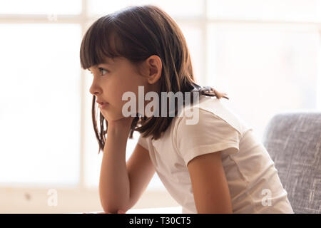 Side view preschool adorable girl sitting on couch at home Stock Photo