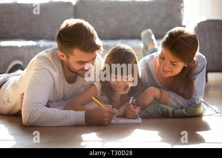 Couple and daughter lying on warm floor and drawing Stock Photo