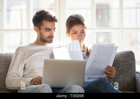 Focused couple sitting on couch reading received formal letter Stock Photo
