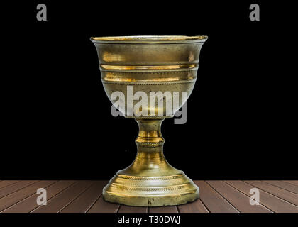 Old chalice on wooden table with black background Stock Photo