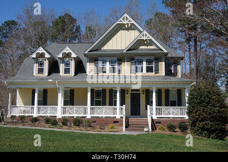 Suburban home with a yellow exterior and a large porch Stock Photo