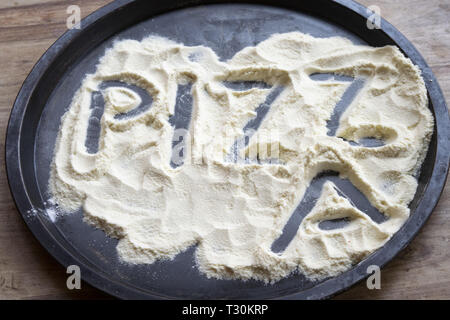 pizza word written on the flour contained in a baking tin Stock Photo