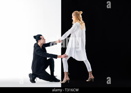 Touching and posing. Dark-haired man with hair bun wearing black suit touching his appealing colleague Stock Photo