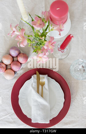 Easter flat lay serving plate with red and white plates, white napkin, gold tableware and eggs, glass and candles. Table top, concept of Easter holida Stock Photo