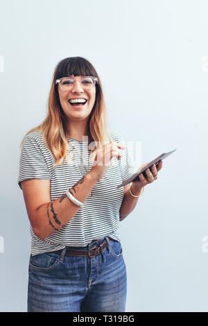 Portrait of a businesswoman standing in office holding a tablet pc. Smiling woman in jeans and tshirt using a tablet pc in office.
