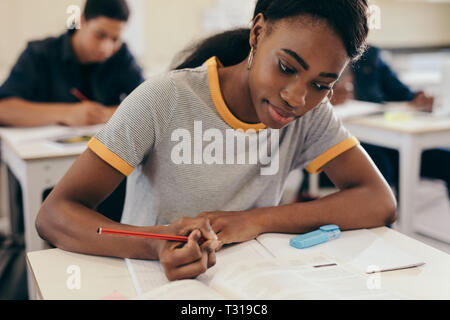 Female student writing notes during a lecture in classroom. Young woman studying at the university. Stock Photo