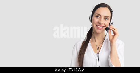 Consultant of call center in headphones on gray background. Helpline operator with headset Stock Photo