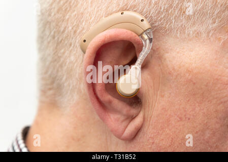 Hearing aid in the ear of aged old man. Senior using modern hearing aid Stock Photo