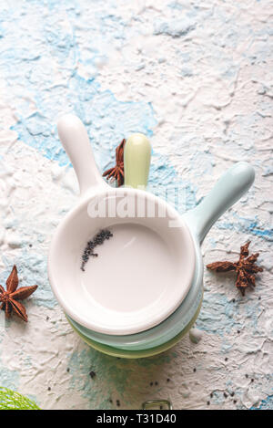 Vertical photo with top view on three small bowls or cups. Cups have simple holder. Each cup has different color - white, blue and green. Spices are s Stock Photo