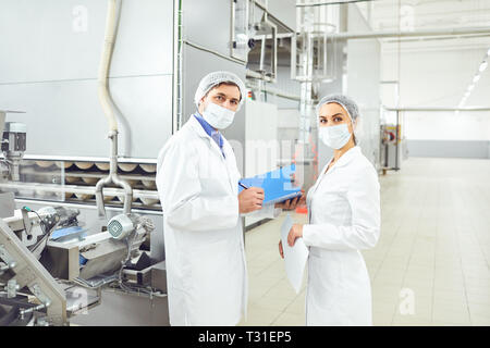 People technologists in masks at food factory. Stock Photo