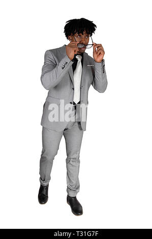 A handsome African American man in a light gray suit putting on his sunglasses and walking, isolated for white background Stock Photo