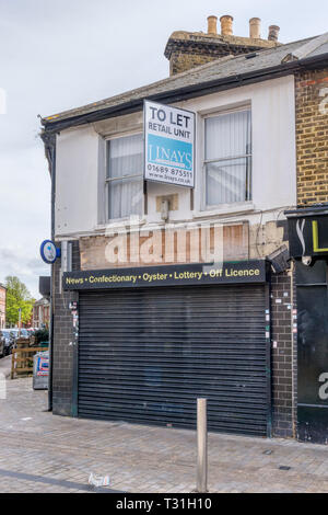 Closed newsagent and corner shop with estate agent's To Let sign. Stock Photo