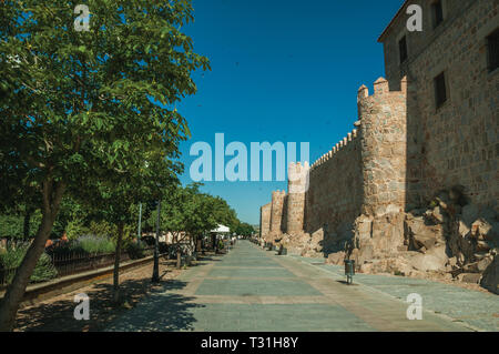 Pedestrian promenade with trees beside large city wall at Avila. With an imposing wall around the gothic city center in Spain. Stock Photo