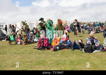 People in costumes sitting on the West Hill waiting for main event to take place on during Jack in the Green festival, Hastings, East Sussex, UK Stock Photo