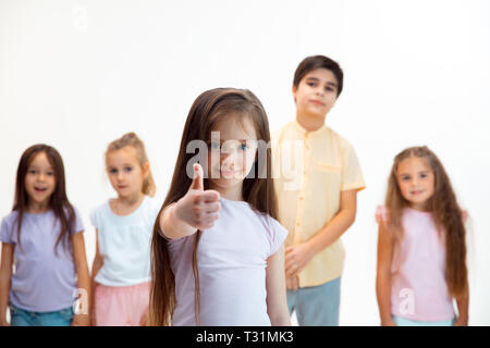 The portrait of happy cute little kids boy and girls in stylish casual clothes looking at camera against white studio wall. Kids fashion and human emotions concept Stock Photo