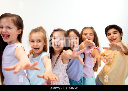 The portrait of happy cute little kids boy and girls in stylish casual clothes looking at camera against white studio wall. Kids fashion and human emotions concept Stock Photo