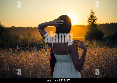 slim young brunette woman looks at sunset in summer Stock Photo