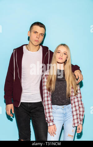 We are friends. Close up fashion portrait of two young cool hipster girl and boy wearing jeans wear. Studio shot of two models having fun and making serious faces. Stock Photo