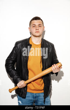 Sport games. Close up fashion portrait of young cool hipster boy wearing jeans wear. Man with a baseball bat. Stock Photo