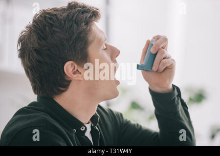side view of handsome man using inhaler at home Stock Photo