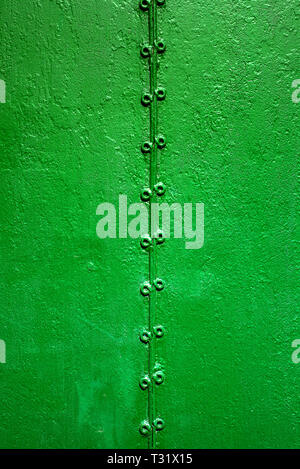 Two part old rusty metal welded by welding and painted green on old rough surface. Verical texture Stock Photo