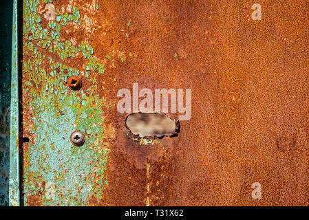 Old rusty metal with hole, painted green which becames orange from rust. Horizontal texture of cracks and peels paint on rusty steel Stock Photo